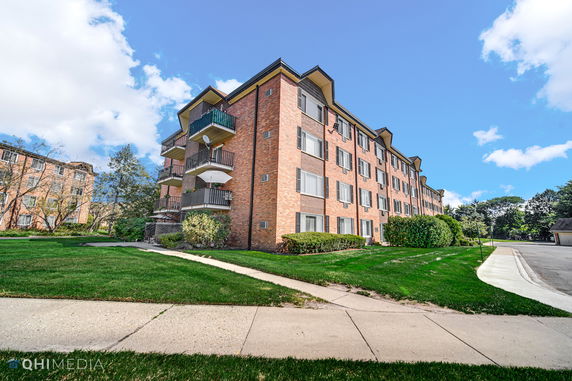 Front view of a multi-story brick apartment building with balconies.