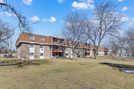 Front view of a multi-story residential building with brick facade and balconies.
