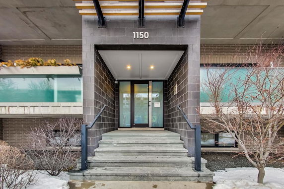 Front view of a modern building entrance with steps leading to a glass door.