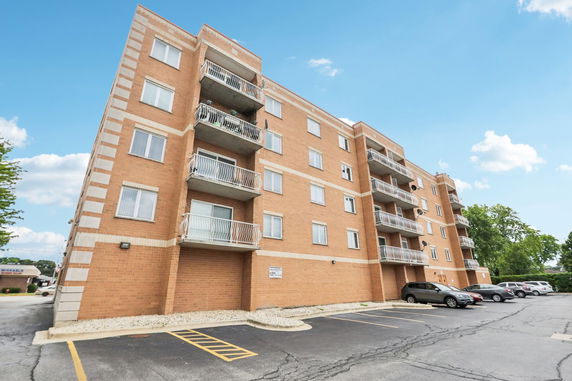 Front view of a multi-story brick apartment building with balconies.
