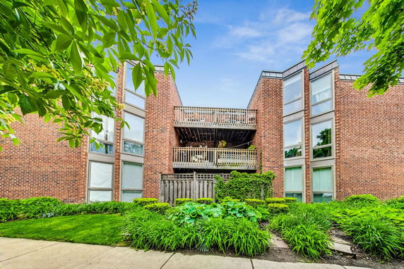 Front view of a three-story brick apartment building with balconies.