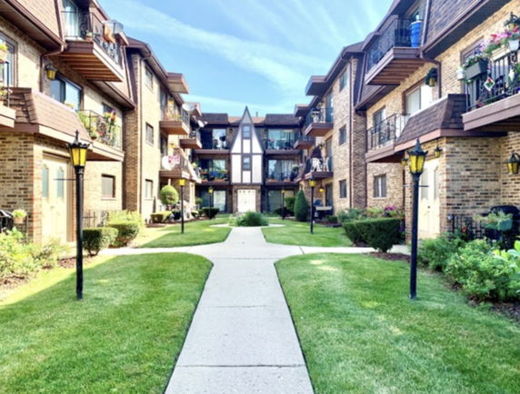 Front view of a multi-story apartment building with balconies and a central pathway.
