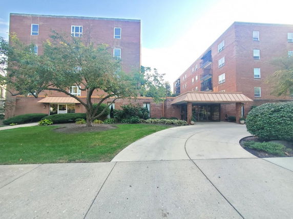 Front view of a multi-story brick building with a circular driveway.