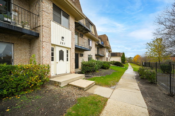 Front view of a multi-story residential building with balconies and entrance.