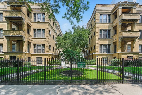 Front view of a multi-story brick apartment building with balconies.