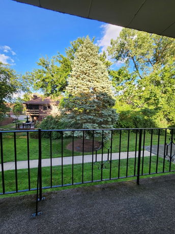 Panoramic view from a balcony overlooking a lawn and trees.
