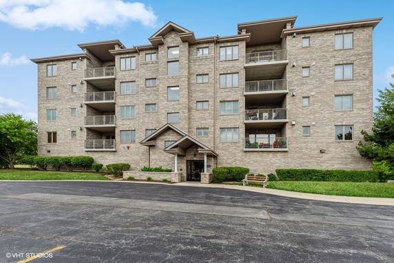 Front view of a multi-story apartment building with balcony and entrance.