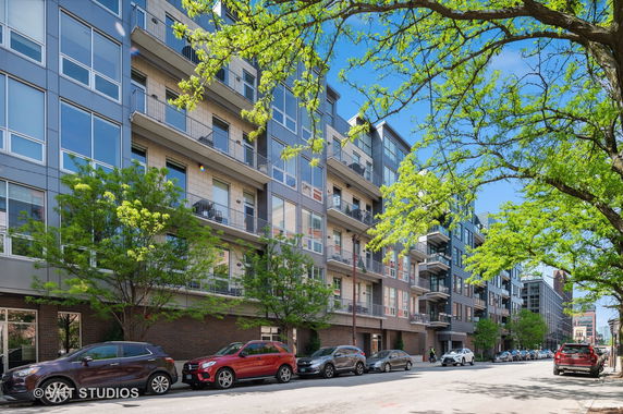 Front view of a multi-story apartment building with large windows and balconies.
