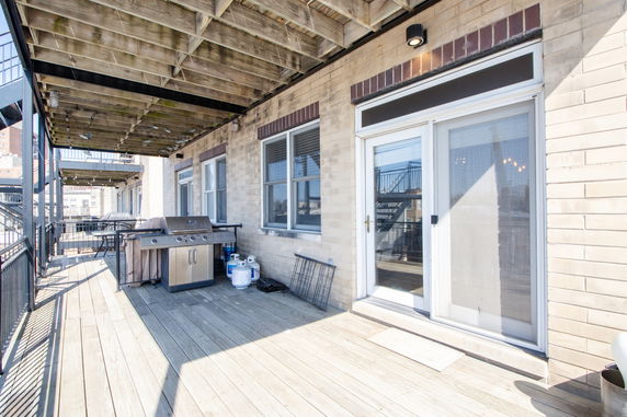 Rooftop deck with a grill and wooden flooring.