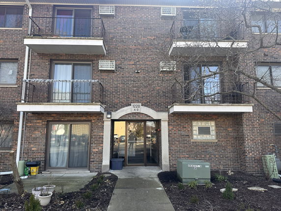 Front view of a multi-story brick building with balconies and a central entrance.