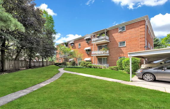 Front view of a multi-story brick building with balconies and a carport.