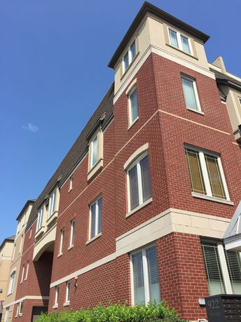 Front view of a multi-story brick building with multiple windows and a tower-like structure.