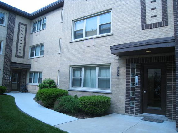 Front view of a multi-story brick apartment building entrance.