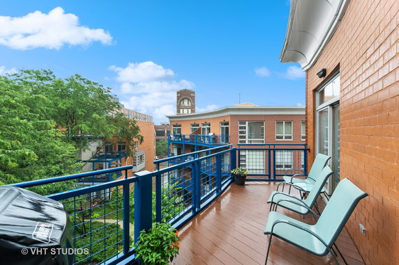 View from a balcony showing adjacent brick buildings and trees.