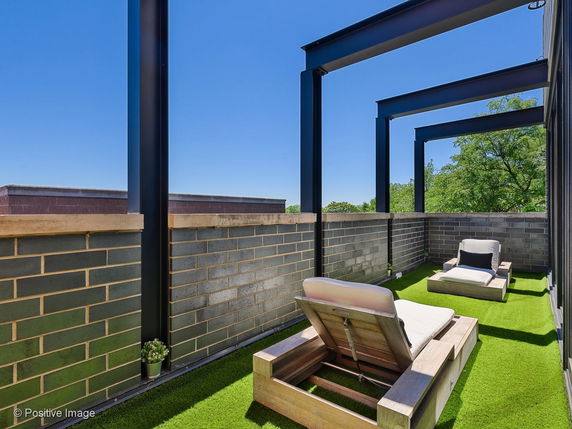 Rooftop with lounge chairs and artificial grass.