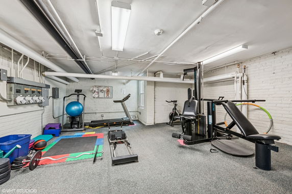 Indoor gym with exercise equipment including a treadmill, stationary bike, and weight machine.