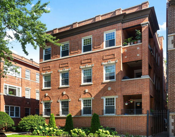 Front view of a multi-story brick apartment building with balconies.