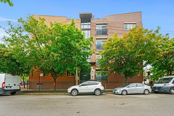 Front view of a multi-story brick building with trees partially obstructing the facade.