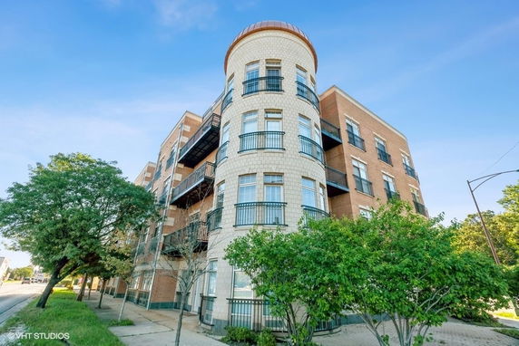 Front view of a multi-story building with a rounded corner tower and balconies.