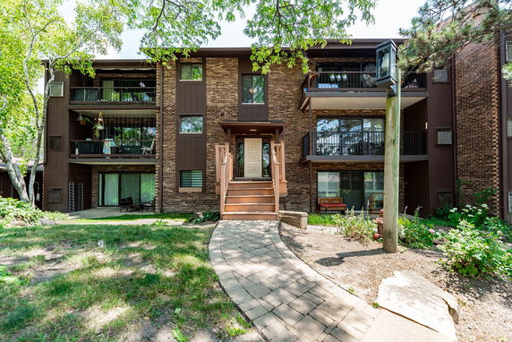 Front view of a brick and wood multi-story apartment building with balconies.