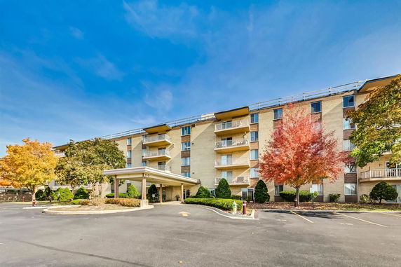 Front view of a multi-story residential building with balconies and a covered entrance.