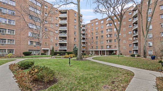 Front view of a multi-story brick apartment building with balconies.