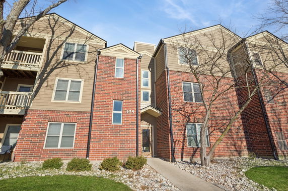 Front view of a multi-story apartment building with brick and siding exterior.