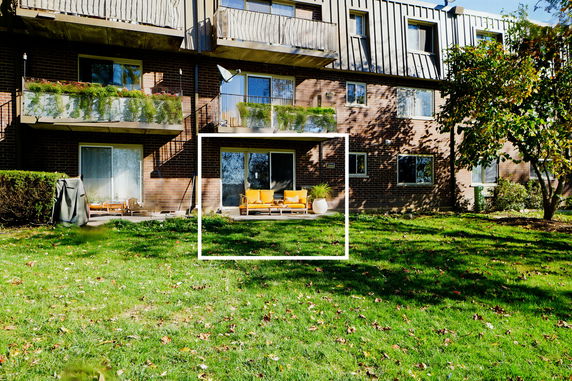 Front view of a multi-story brick building with balconies and outdoor seating area.
