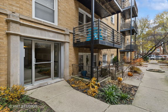 Front view of a brick apartment building with balconies and entrance door.