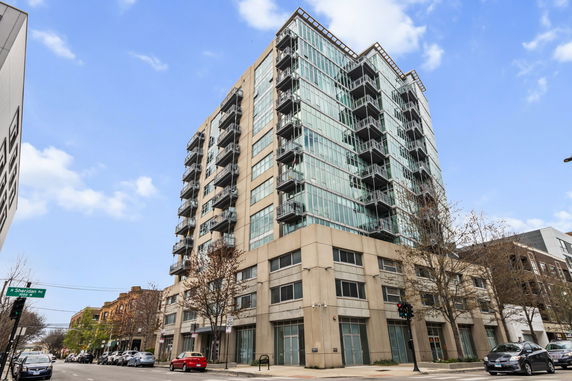 Front view of a multistory apartment building with glass balconies.