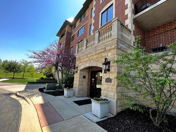 Front view of a multi-story brick building with an arched entryway and decorative lighting.