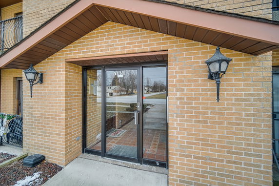 Front view of a building entrance with glass doors and brick exterior.