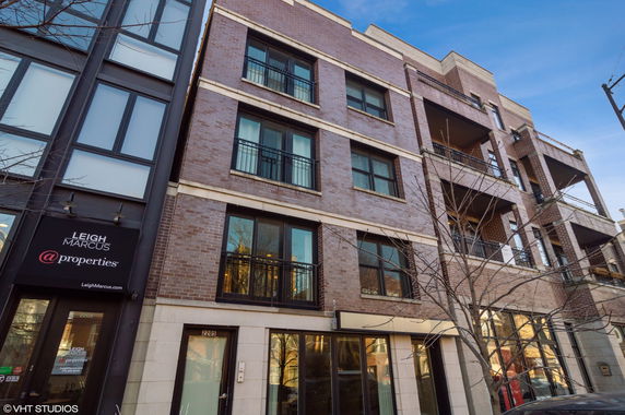 Front view of a multi-story brick building with large windows and balconies.