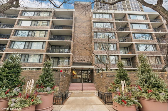 Front view of a multi-story brick residential building with balconies.