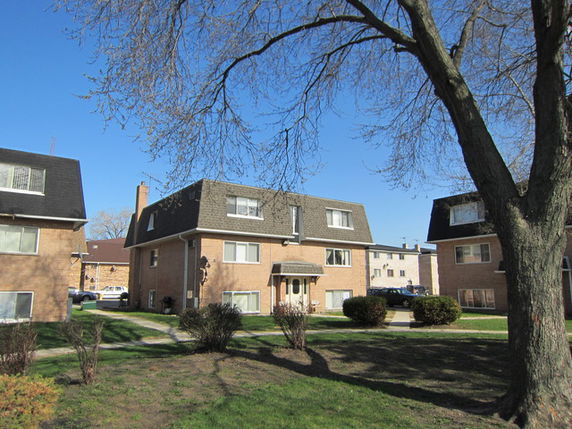 Front view of a multi-story brick residential building with a sloped roof.