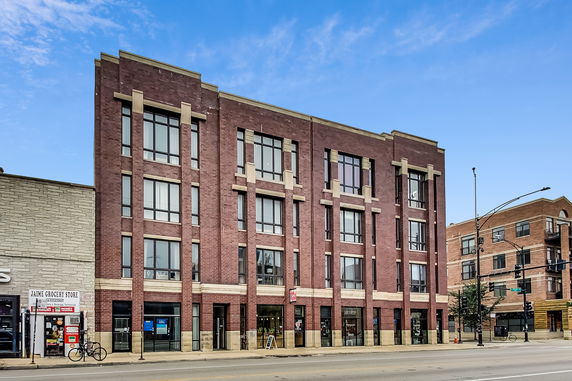 Front view of a multi-story brick building with large windows.