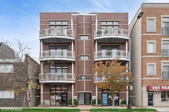 Front view of a multi-story building with balconies and brick facade.
