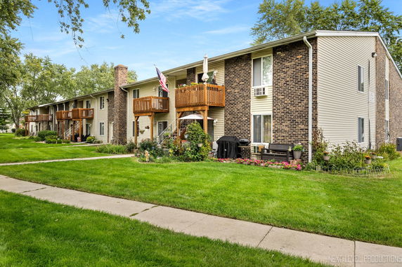 Front view of a two-story building with wooden balconies and brick accents.