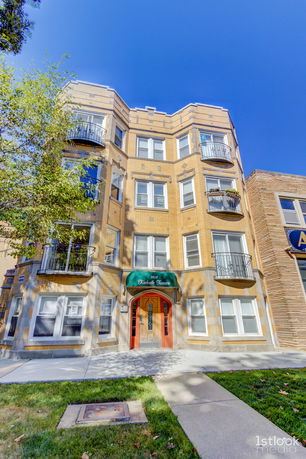 Front view of a multi-story building with balconies and a central entrance.