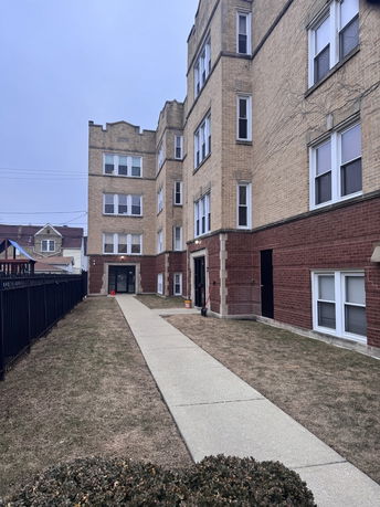 Front view of a multi-story brick apartment building with a central walkway.
