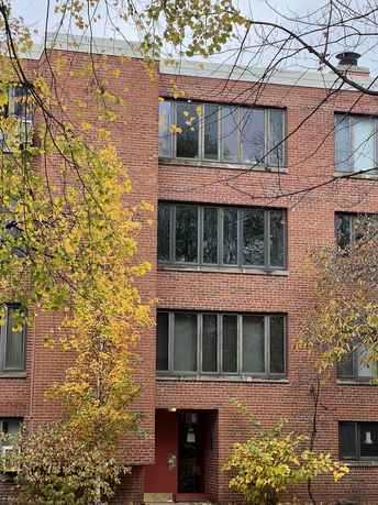 Front view of a multi-story brick building with large windows.