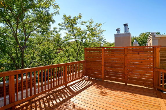 Wooden rooftop deck with railing and chimneys visible.