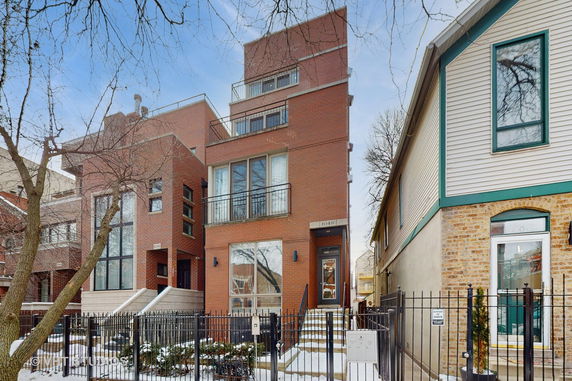 Front view of a multi-story brick house with large windows and balconies.