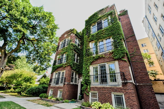 Front view of a multi-story brick building with ivy-covered facade.