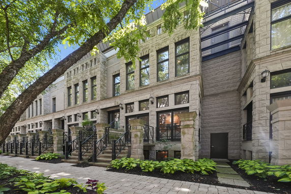Front view of a row of stone townhouses with large windows and metal railings.