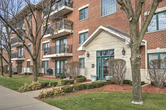 Front view of a multi-story brick residential building with balconies.