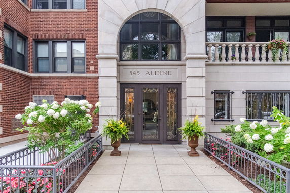 Front view of a multi-story brick building with ornate entrance and decorative railing.