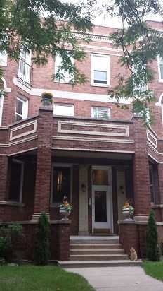 Front view of a multi-story brick building with a central entrance and balconies.