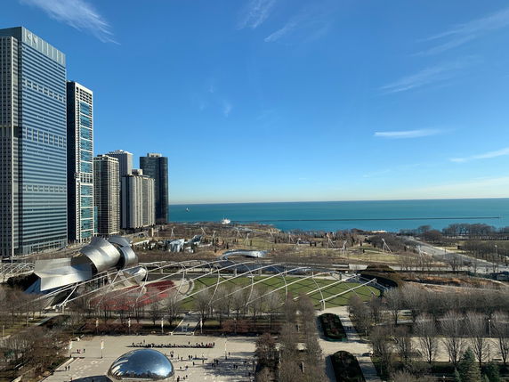 Panoramic view of a cityscape with modern buildings and a large body of water in the background.