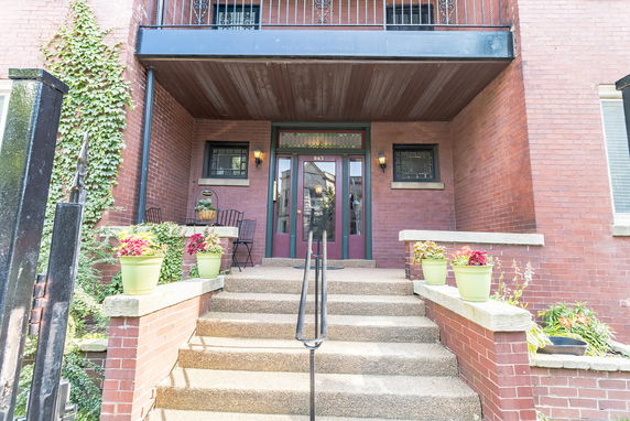 Front view of a brick building entrance with steps and railing.
